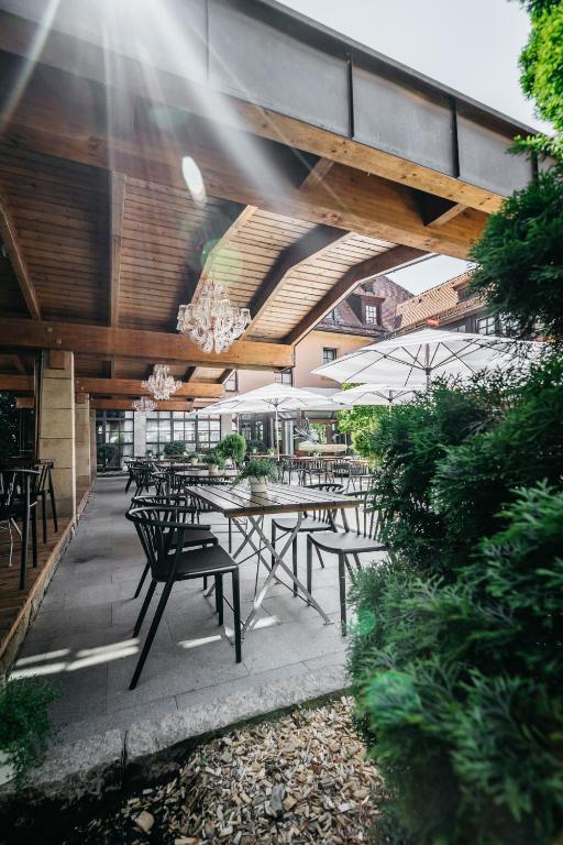 eine Außenterrasse mit Tischen, Stühlen und einem Kronleuchter in der Unterkunft Hotel Riesengebirge in Neuhof an der Zenn
