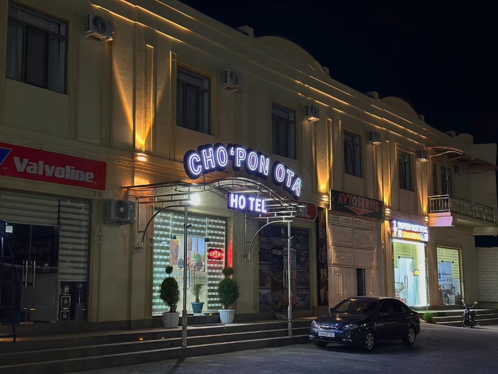 撒馬爾罕的住宿－CHO'PON OTA Hotel，夜间停在大楼前的汽车