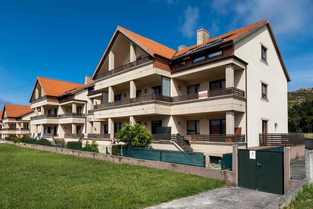 a large white building with a red roof at Apartamento Ancora Caldebarcos in San Mamede de Carnota