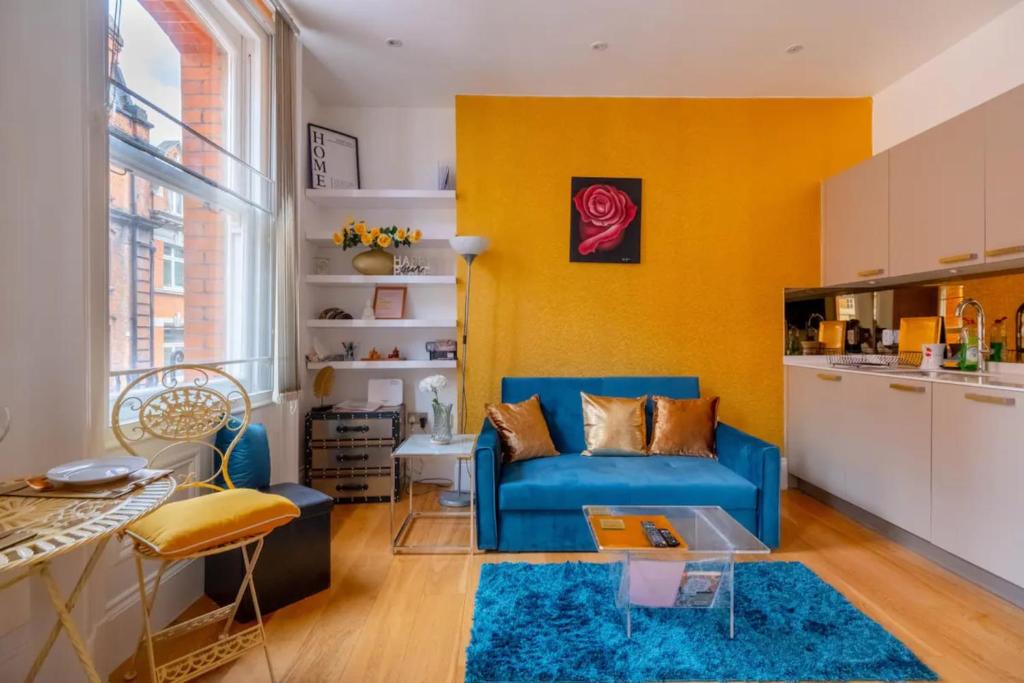 a living room with a blue couch and yellow walls at Central & Cosy 1BD Flat - Soho in London