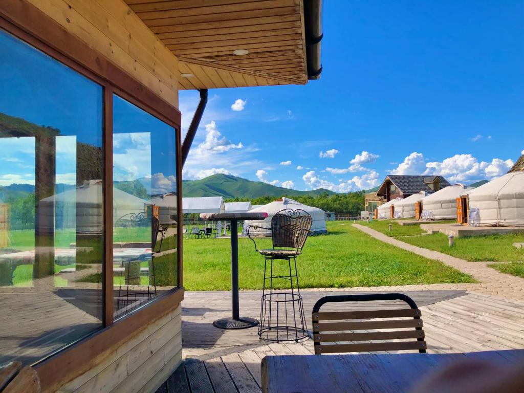 d'une terrasse avec une table, des chaises et des fenêtres. dans l'établissement Kayak Camp, Tsonjinboldog, à Narst