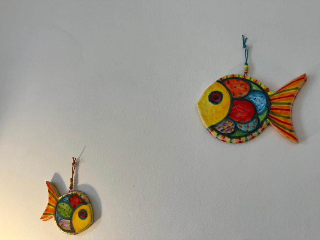 dois ornamentos de peixe estão pendurados numa parede em Appartamento Stella em Levanto