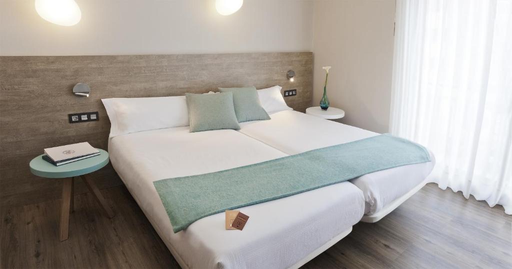 Un dormitorio con una gran cama blanca y una mesa en Hotel Dos Rios Central, en Aínsa