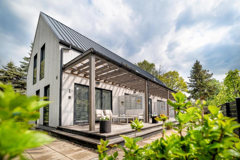 a small white house with a black roof at Apartamenty Tęsknoty 10 in Dziwnów