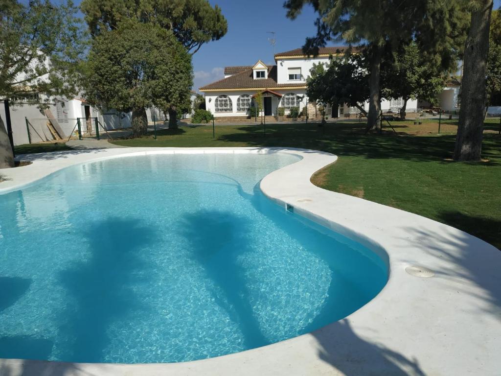 een zwembad in een tuin met een huis op de achtergrond bij Hacienda Laguna Seca - Apart. Hibisco in Chiclana de la Frontera