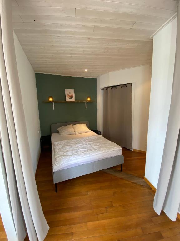 a bedroom with a bed with a green wall at Le logis des Halles in Cerizay