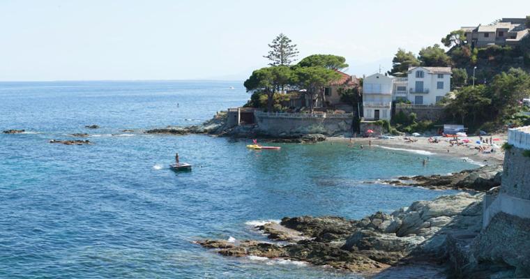 una playa con gente en un barco en el agua en Cap Corse une villa dans un nid de verdure, en San-Martino-di-Lota
