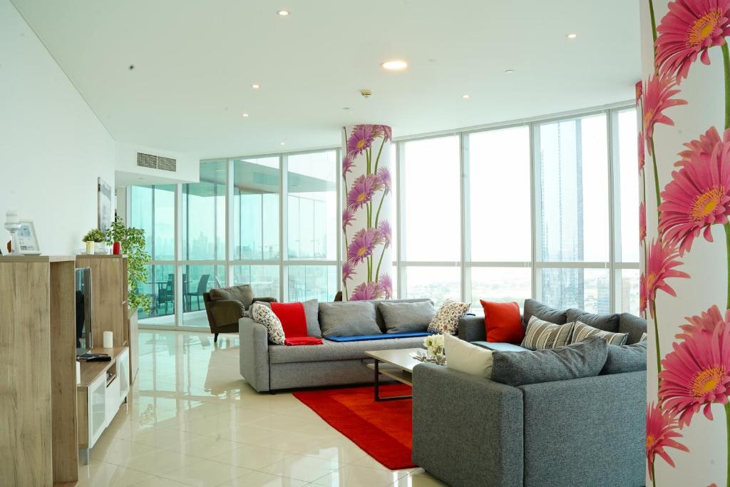 Luxurious Penthouses في دبي: غرفة معيشة مع أريكة رمادية وسجادة حمراء