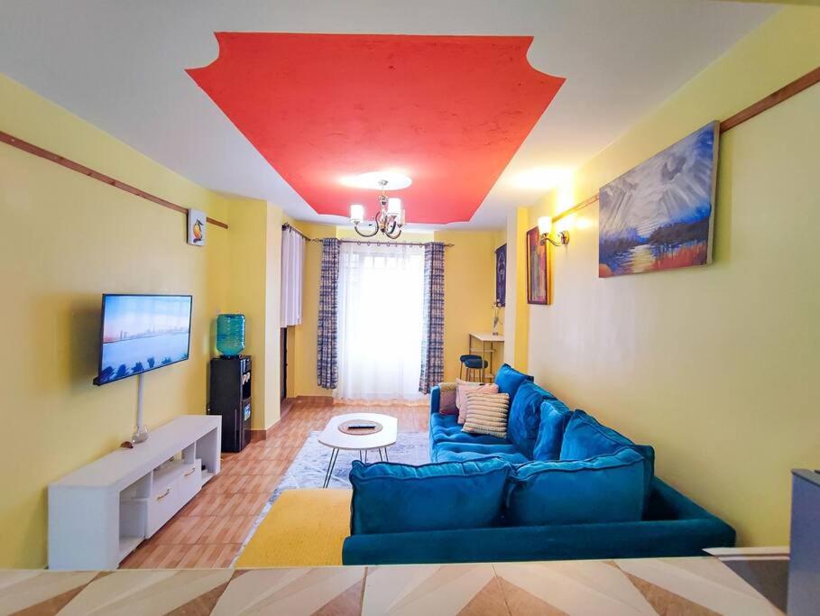 een woonkamer met een blauwe bank en een rood plafond bij Cosy One bedroom Thika Road,TRM in Nairobi