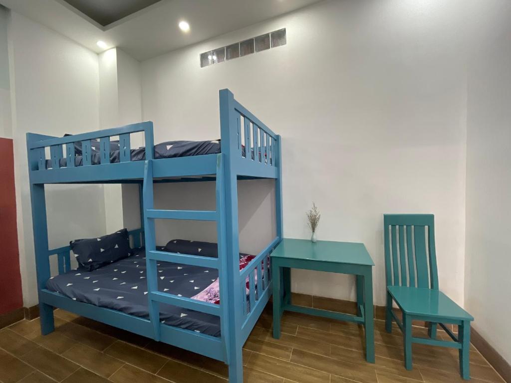 a blue bunk bed with a table and a chair at HO GIA AN Home - Phòng chung in Can Tho