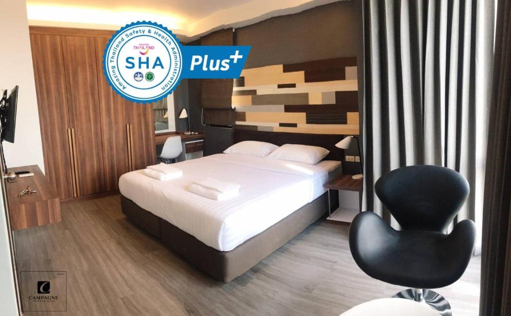 um quarto de hotel com uma cama e uma cadeira preta em Campagne Hotel and Residence - SHA Plus em Pathum Thani