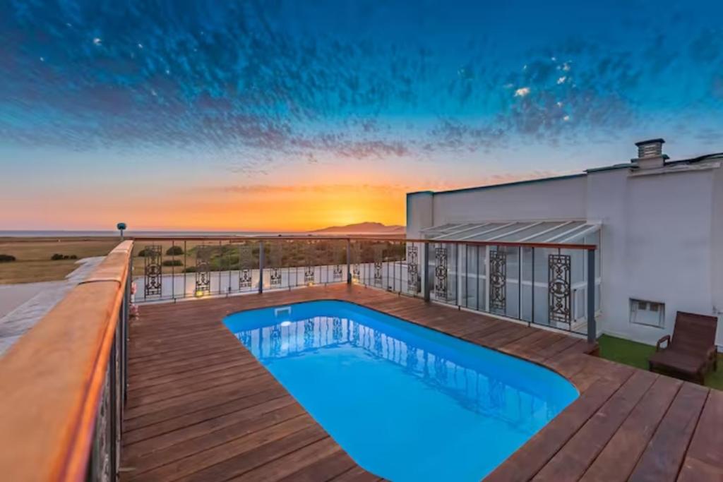 een zwembad op een terras met de zonsondergang op de achtergrond bij BOMBAYARTE APARTHOTEL TARIFA in Tarifa