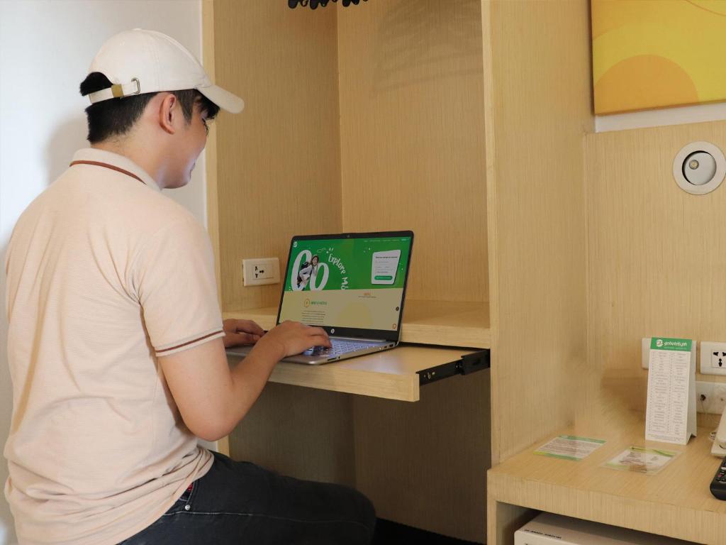 un hombre sentado en un mostrador usando un ordenador portátil en Go Hotels Ermita, Manila en Manila