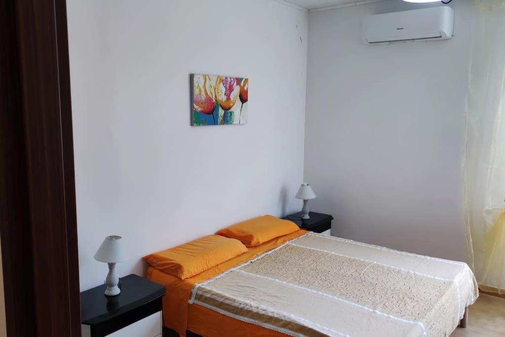 um quarto com uma cama com lençóis laranja e 2 candeeiros em Appartamento vista mare em Nicotera Marina