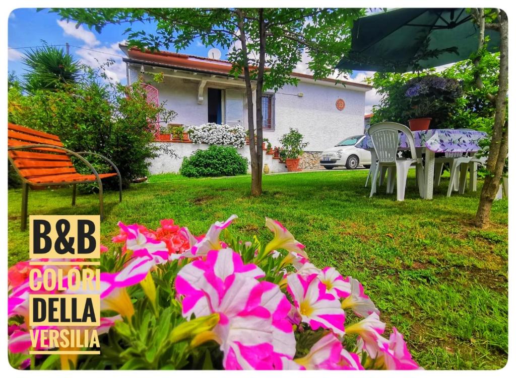 een huis met een tuin met stoelen en bloemen bij colori della versilia in Montignoso