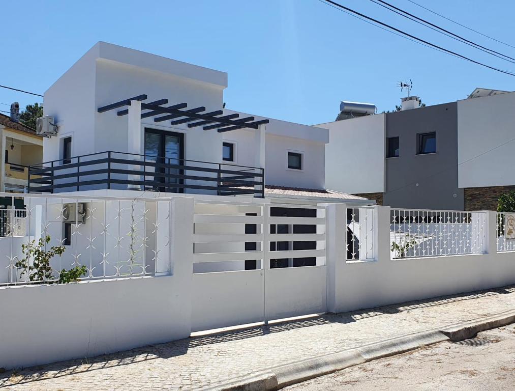 a white house with a white fence at Aroeira House in Aroeira