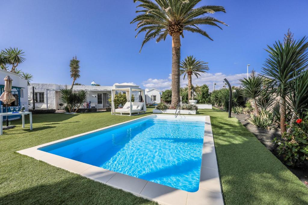 een zwembad in een tuin met palmbomen bij Villas New Lanzasuites in Playa Blanca