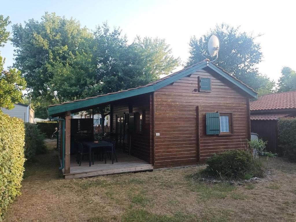 een houten hut met een tafel op een terras bij Chalet calme et agréable in Parentis-en-Born