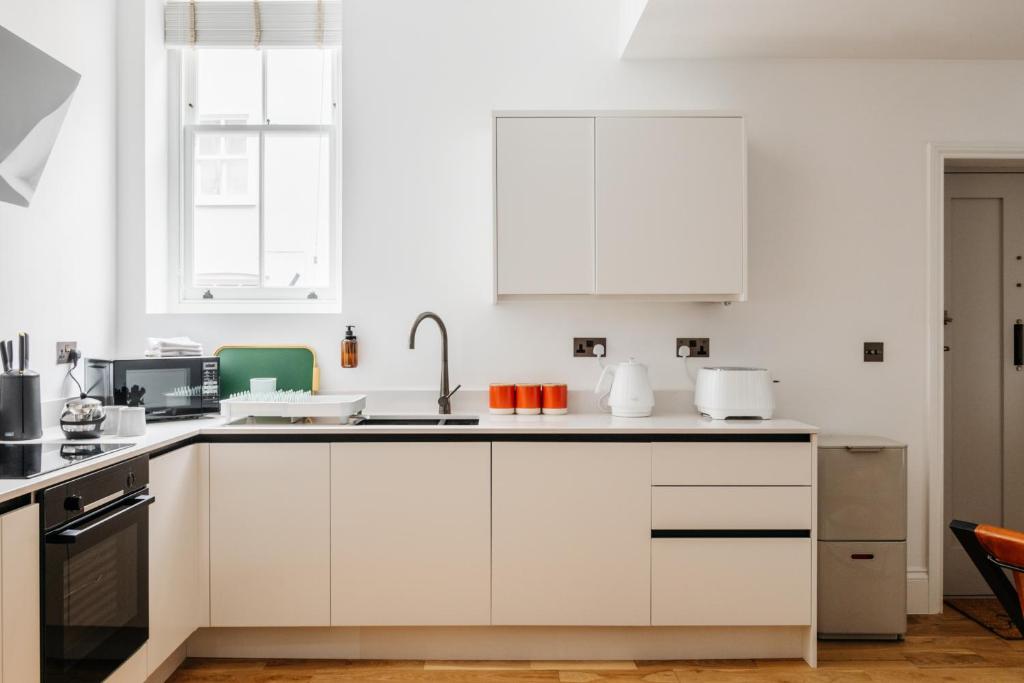 una cocina blanca con armarios y electrodomésticos blancos en Jesticos, Retro Modernised Luxury Very Central Historic Home Free Parking en Canterbury