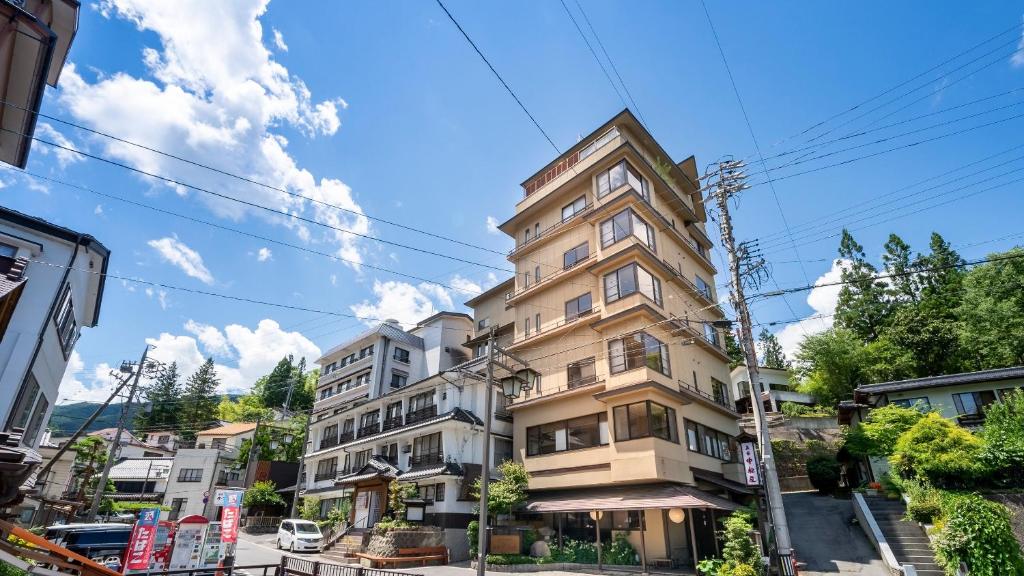 wysoki budynek apartamentowy przy ulicy miejskiej w obiekcie Nakamatsuya Ryokan w mieście Ueda