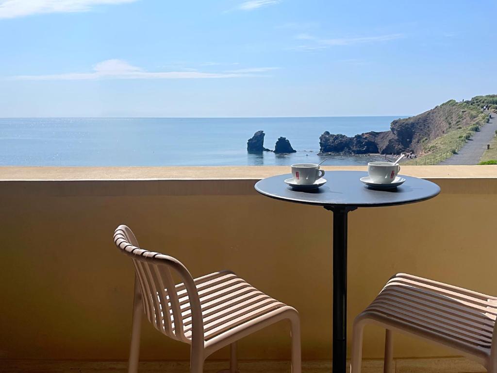 Una mesa con dos sillas y dos tazas. en Hôtel La Grande Conque, en Cap d'Agde