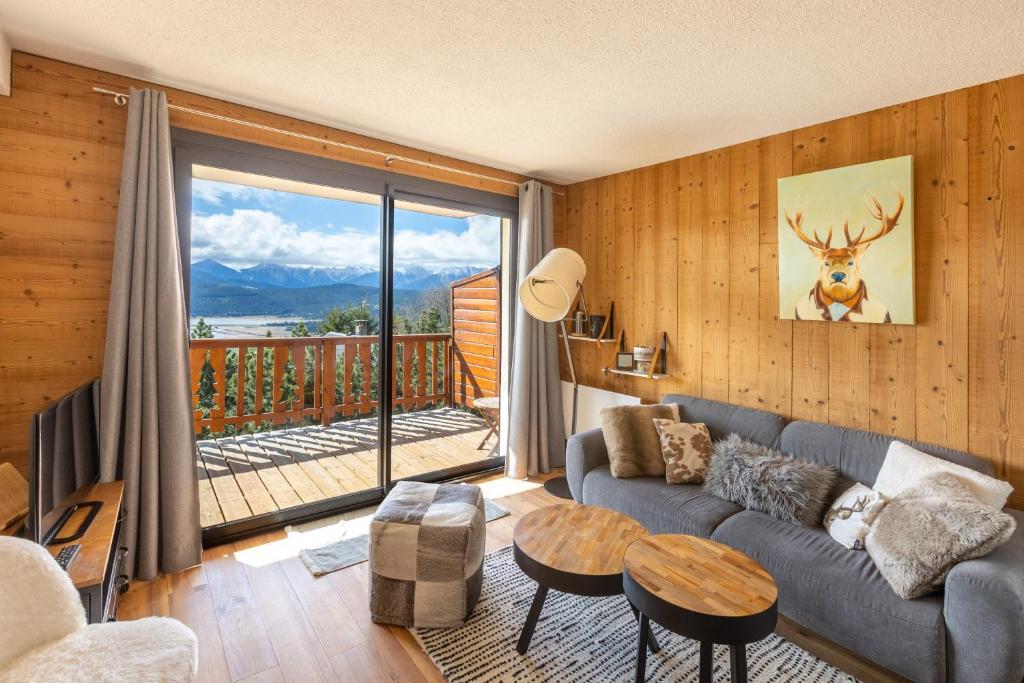 un salon avec un canapé et une grande fenêtre dans l'établissement Le Reflet du Lac - Station ski accessible à pied, aux Angles