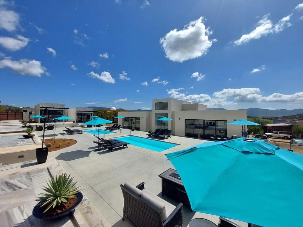 un gran patio con piscina y sombrillas en D'VINO Valle De Guadalupe, en Ensenada