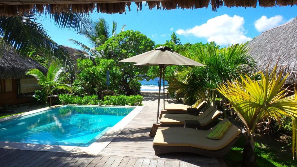 a pool with chairs and an umbrella next to a resort at Green Lodge Moorea in Teavaro