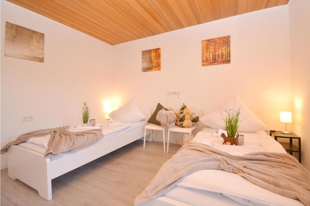 two beds in a room with white walls and wooden ceilings at CO07-HI Apartment in Coburg in Coburg