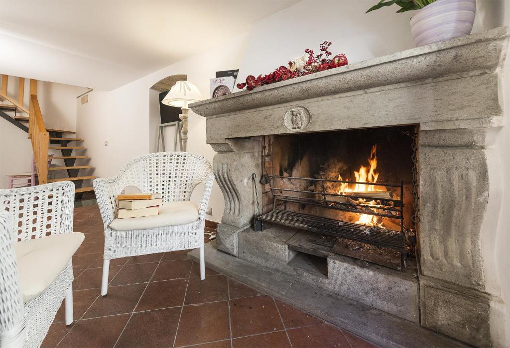 een open haard in een woonkamer met 2 witte stoelen bij B&B I Tre Camini in Tarquinia
