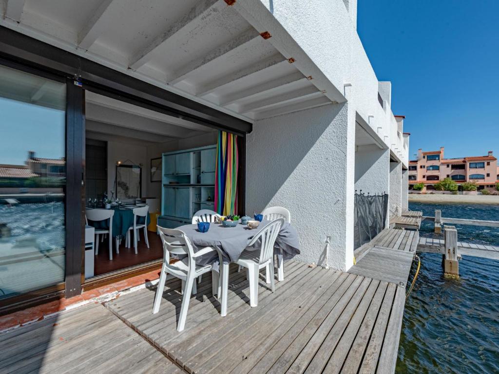 a wooden deck with a table and chairs on the water at Holiday Home Les Brigantins-3 by Interhome in Port Leucate