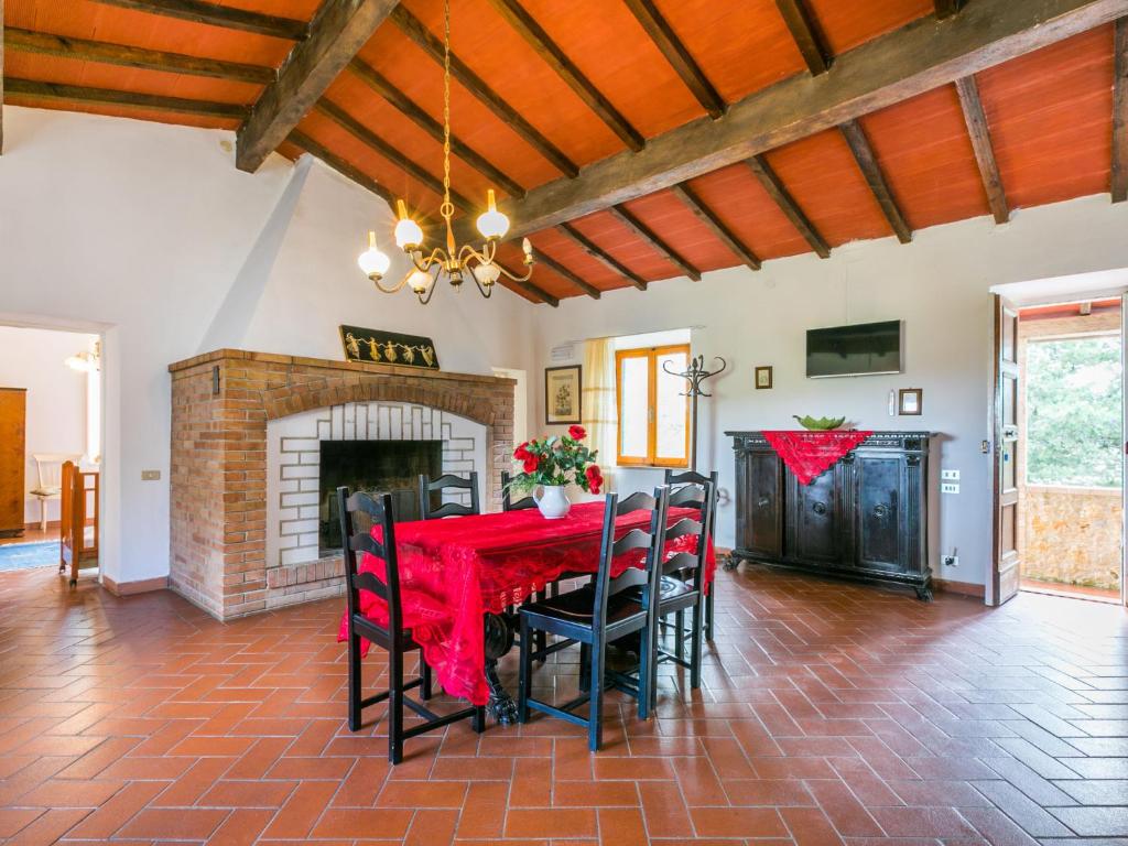 una sala da pranzo con un tavolo e sedie rossi e un camino di Apartment Fattoria Petraglia - Padronale by Interhome a Monteriggioni