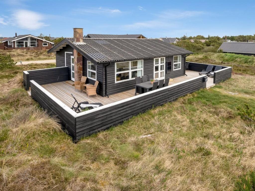 ein Haus mit einer Terrasse auf einem Feld in der Unterkunft Holiday Home Arbnora - 400m from the sea in Western Jutland by Interhome in Bjerregård