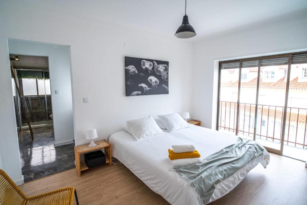 a bedroom with a white bed and a large window at House of PAB in Praia da Areia Branca