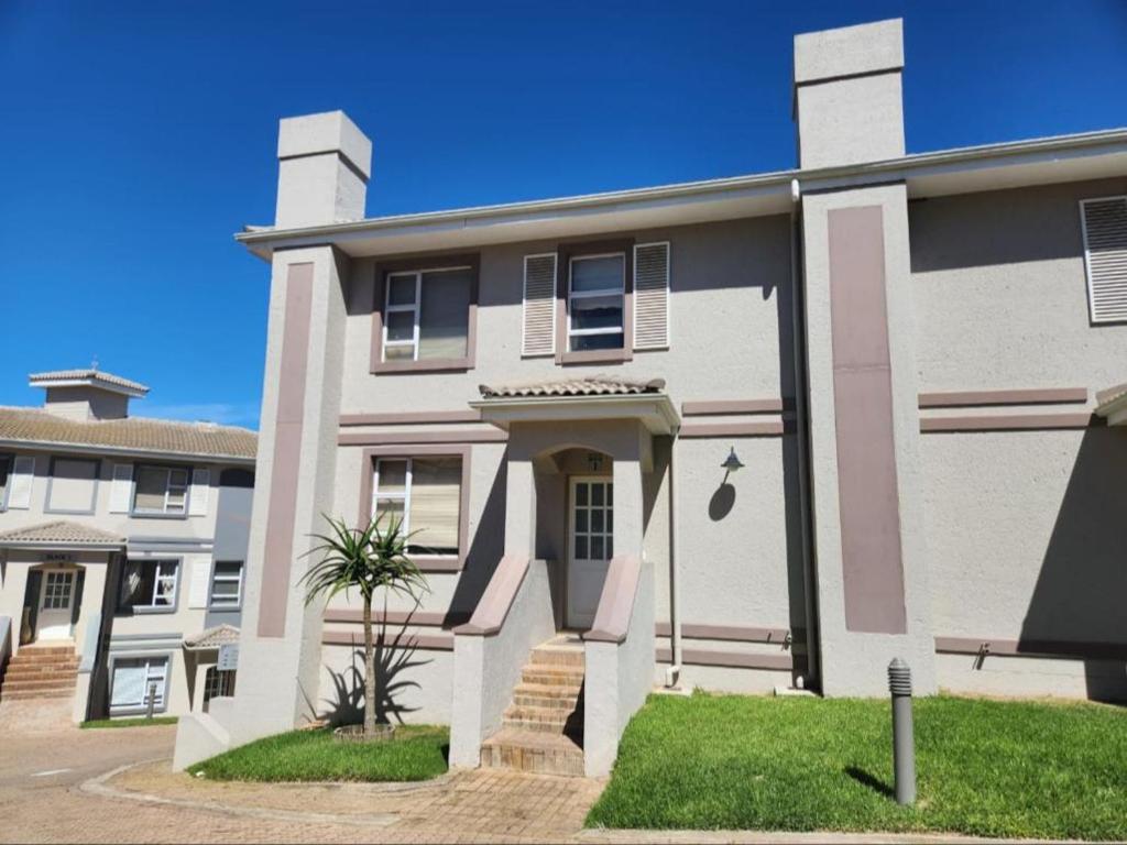 ein weißes Haus mit einer Palme davor in der Unterkunft Pinnacle Point Golf Estate - Golf Villa 10-1 in Mossel Bay