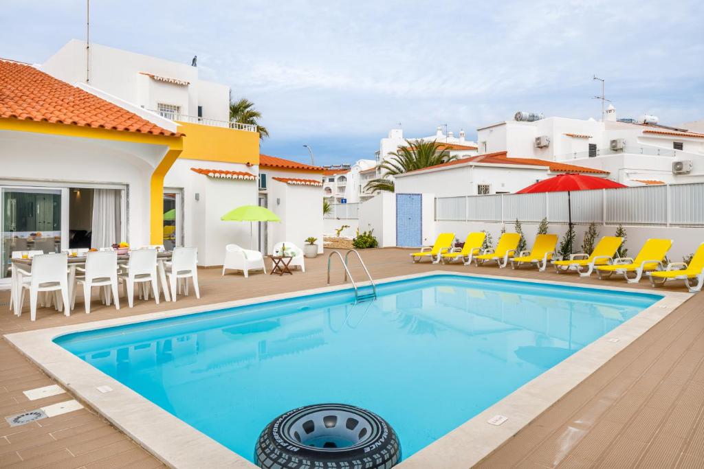 a swimming pool with chairs and umbrellas in a house at Villa Nobre by The Portuguese Butler in Albufeira