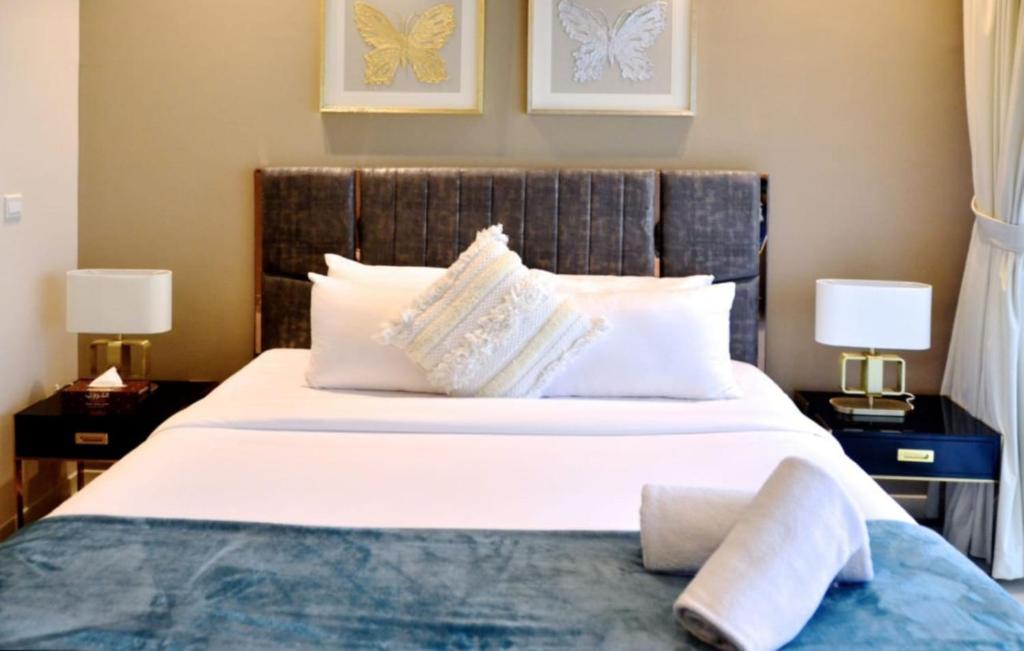um quarto com uma grande cama branca e 2 candeeiros em Elegant Studio in park View JVC em Dubai
