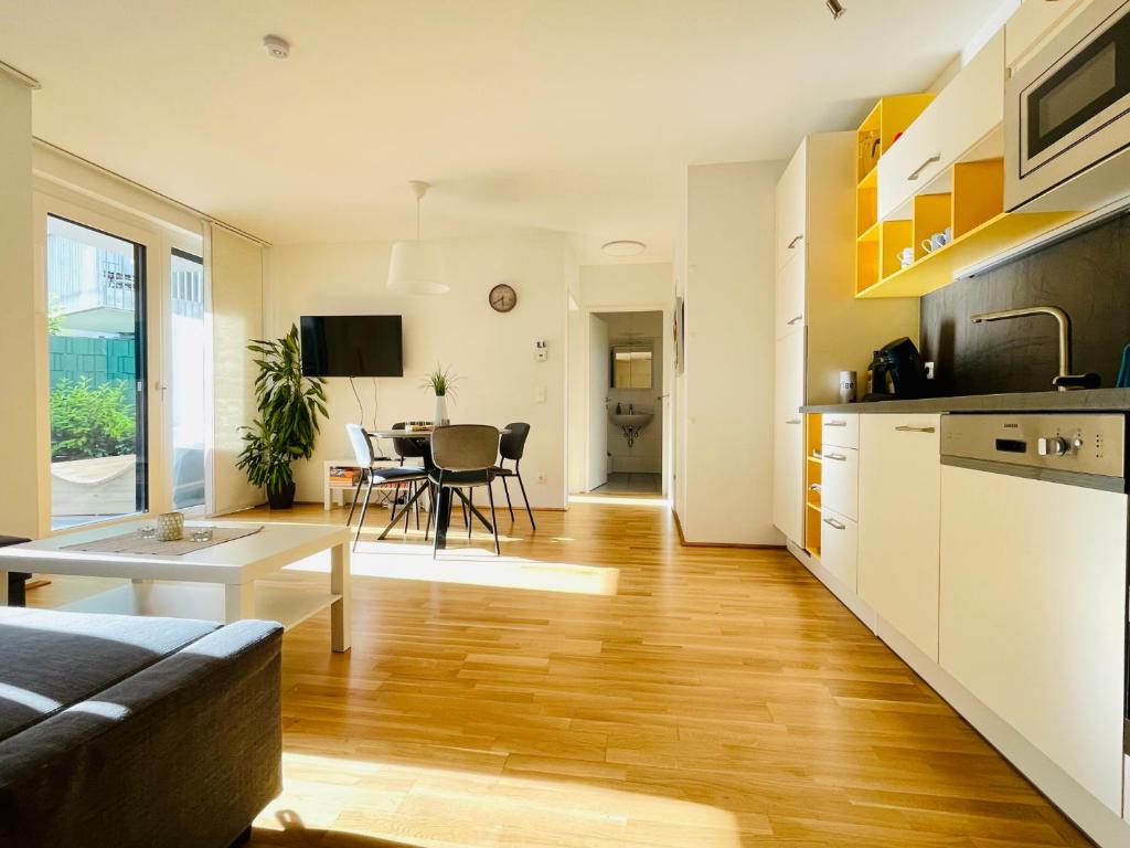 uma cozinha e sala de estar com um sofá e uma mesa em Topmodernes Sonnenwohnen Apartment bei U-Bahn und Therme Wien Oberlaa, 15 min bis Stephansplatz em Viena