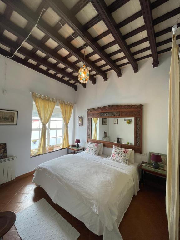 una camera da letto con un grande letto bianco con testiera in legno di Casa Antigua - Terraza con Vistas al Mar a Medina Sidonia