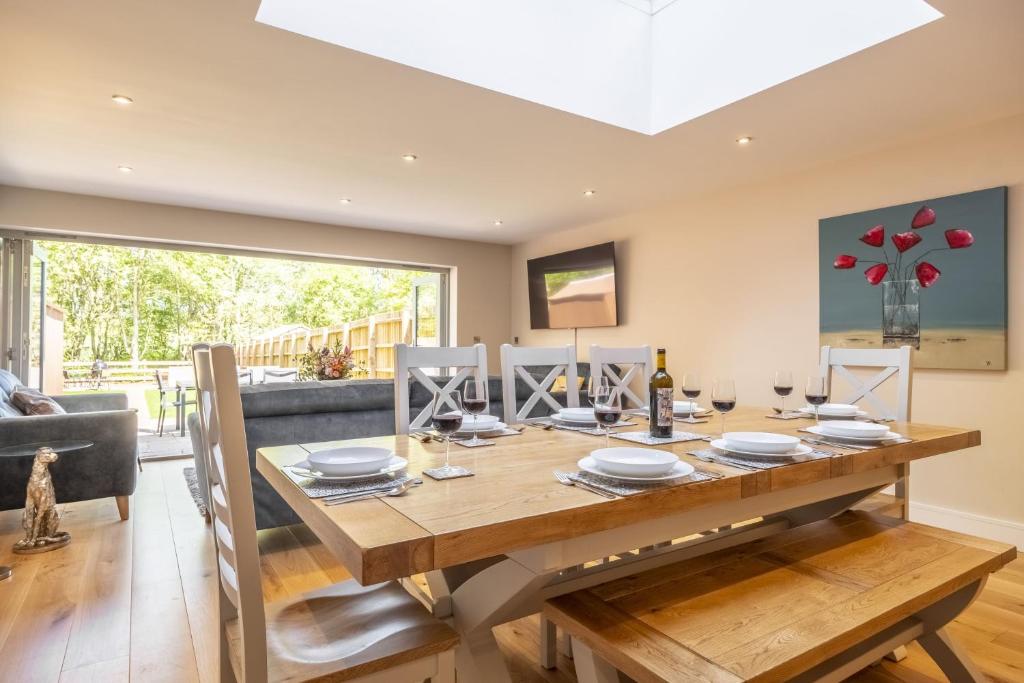 a dining room with a wooden table and a large window at The Goosebec in Burnham Market