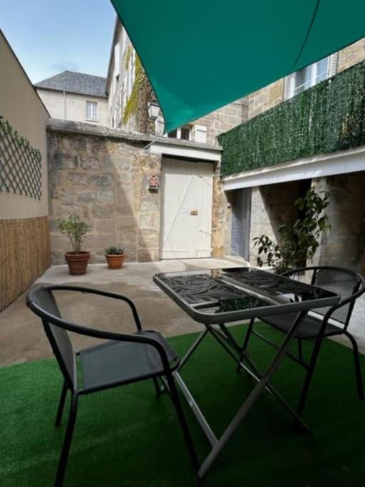 a patio with two chairs and a table and an umbrella at #Le Rue des 2 Porches #F2 avec Cours #HyperCentre in Brive-la-Gaillarde
