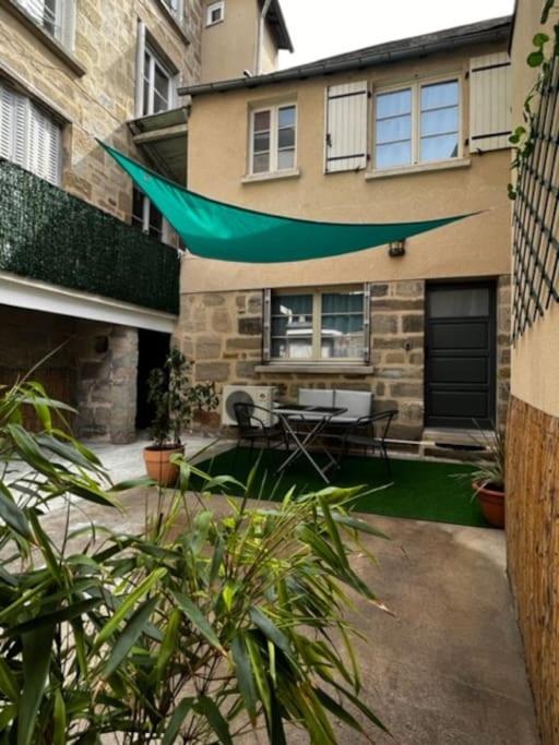 a patio with a green umbrella in front of a building at #Le Rue des 2 Porches #F2 avec Cours #HyperCentre in Brive-la-Gaillarde