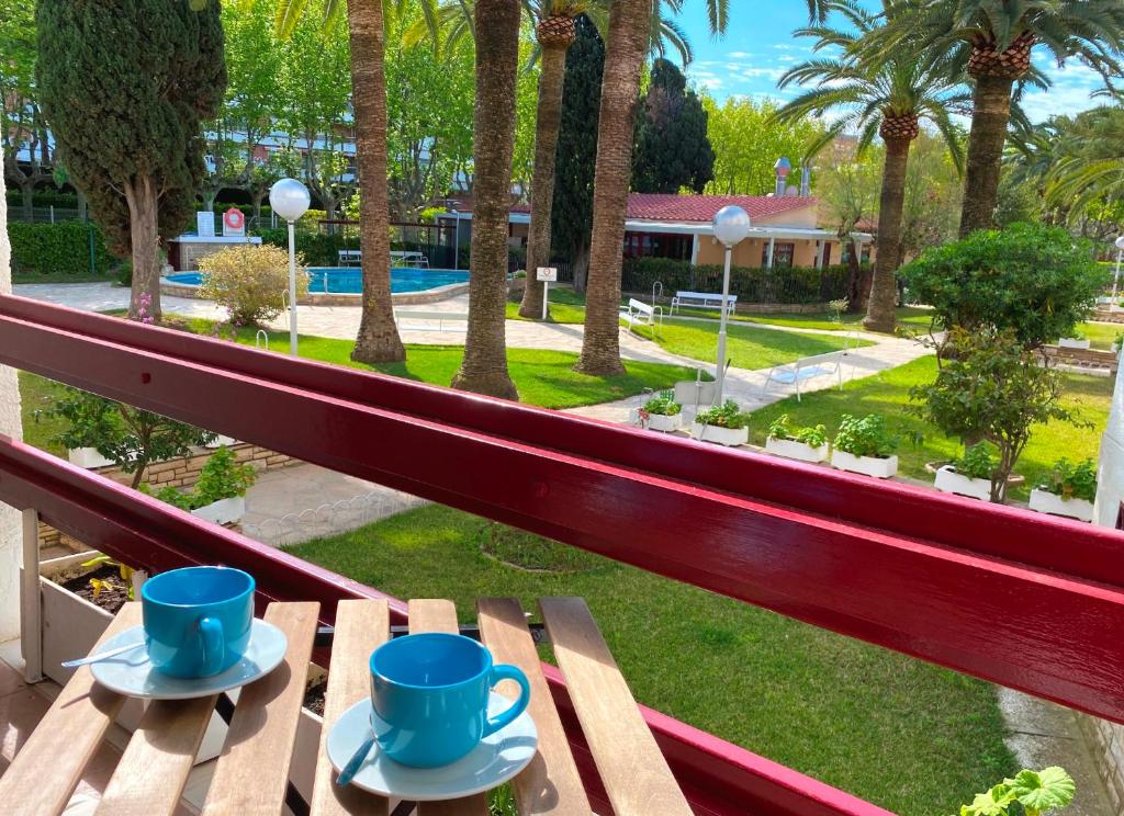 two blue cups and saucers sitting on a bench at Apartamentos Córcega Palmyra in Salou