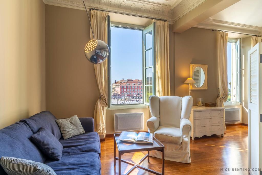 un soggiorno con divano blu, sedia e finestra di Nice Renting - 13 MASSENA - Live A Dream Luxury Loft - Place Massena a Nizza