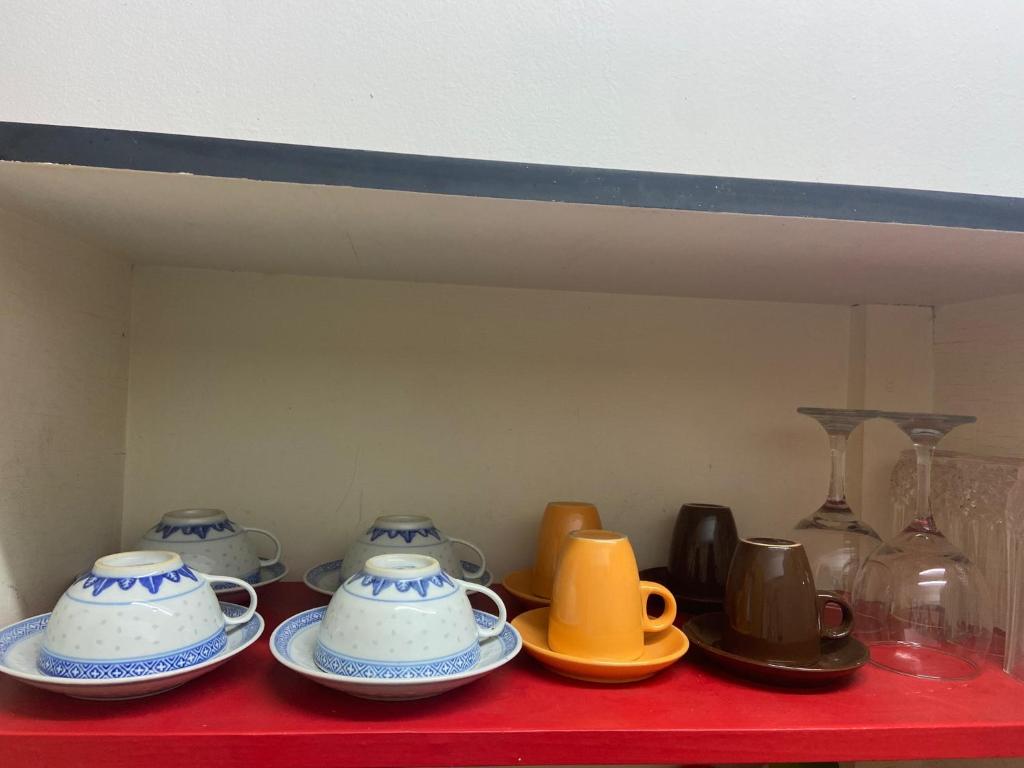 a red table with three tea pots and plates on it at Musty's Home in Famagusta
