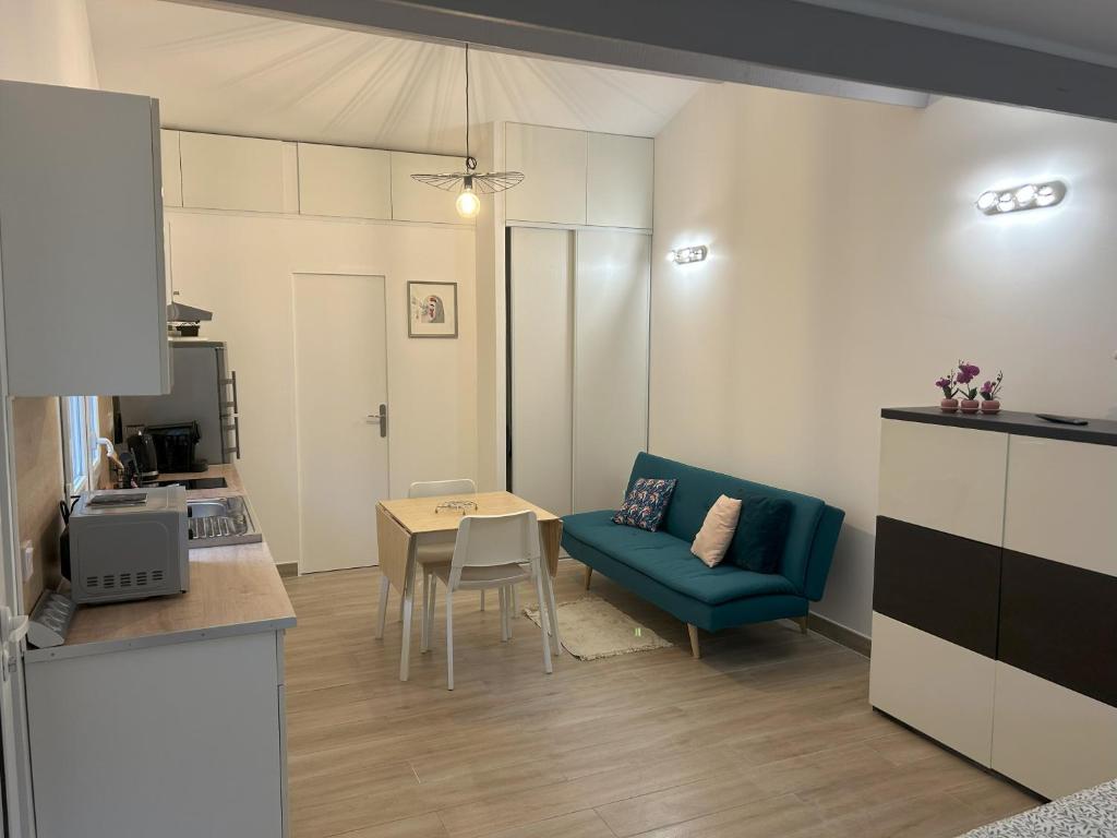 uma sala de estar com uma mesa e um sofá azul em Maison studio Le bois fleuri em Croissy-Beaubourg