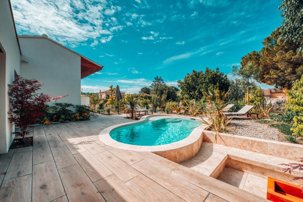 un patio trasero con piscina y terraza de madera en Villa luxe Oasis de Satteva, en LʼIsle-sur-la-Sorgue