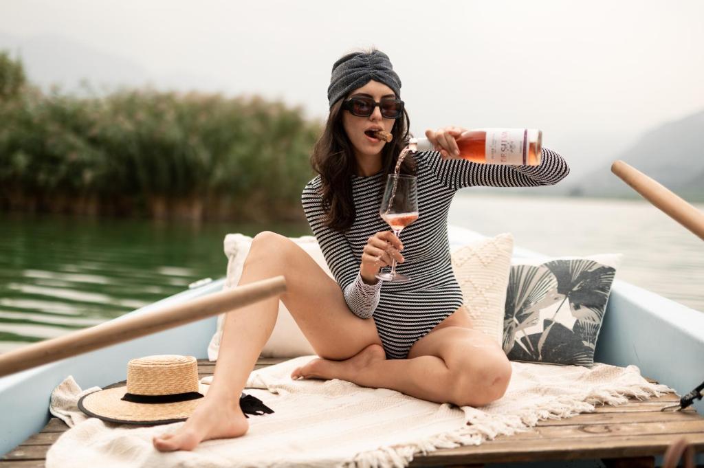 Eine Frau, die auf einem Boot sitzt und ein Glas Wein hält. in der Unterkunft Leuchtenburg am See in Kaltern