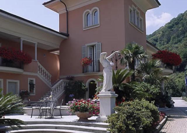 Una statua di una donna in piedi davanti a una casa di Hotel Villa Delle Palme a Cannobio