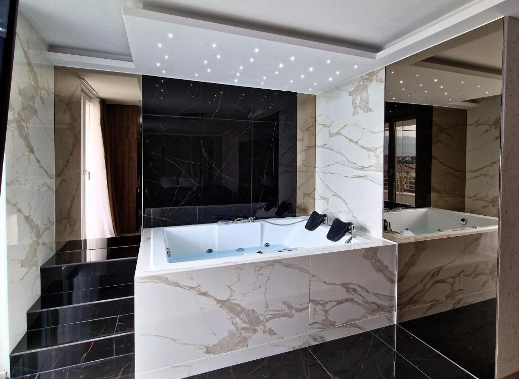a bathroom with a tub and a large mirror at PETKOV5KI.LuxuryApartments in Skopje